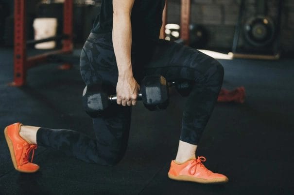 woman doing walking lunges with barbell